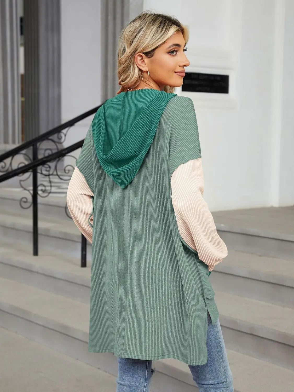 Woman wearing a green and beige double take contrast hooded long sleeve top with pockets standing outdoors