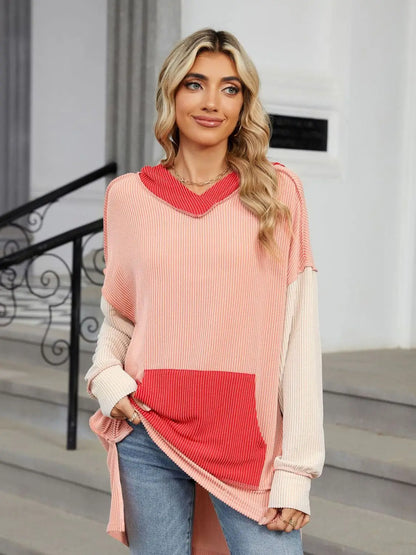 Woman wearing a pink and red double take contrast hooded long sleeve top with pocket and light stretch fabric