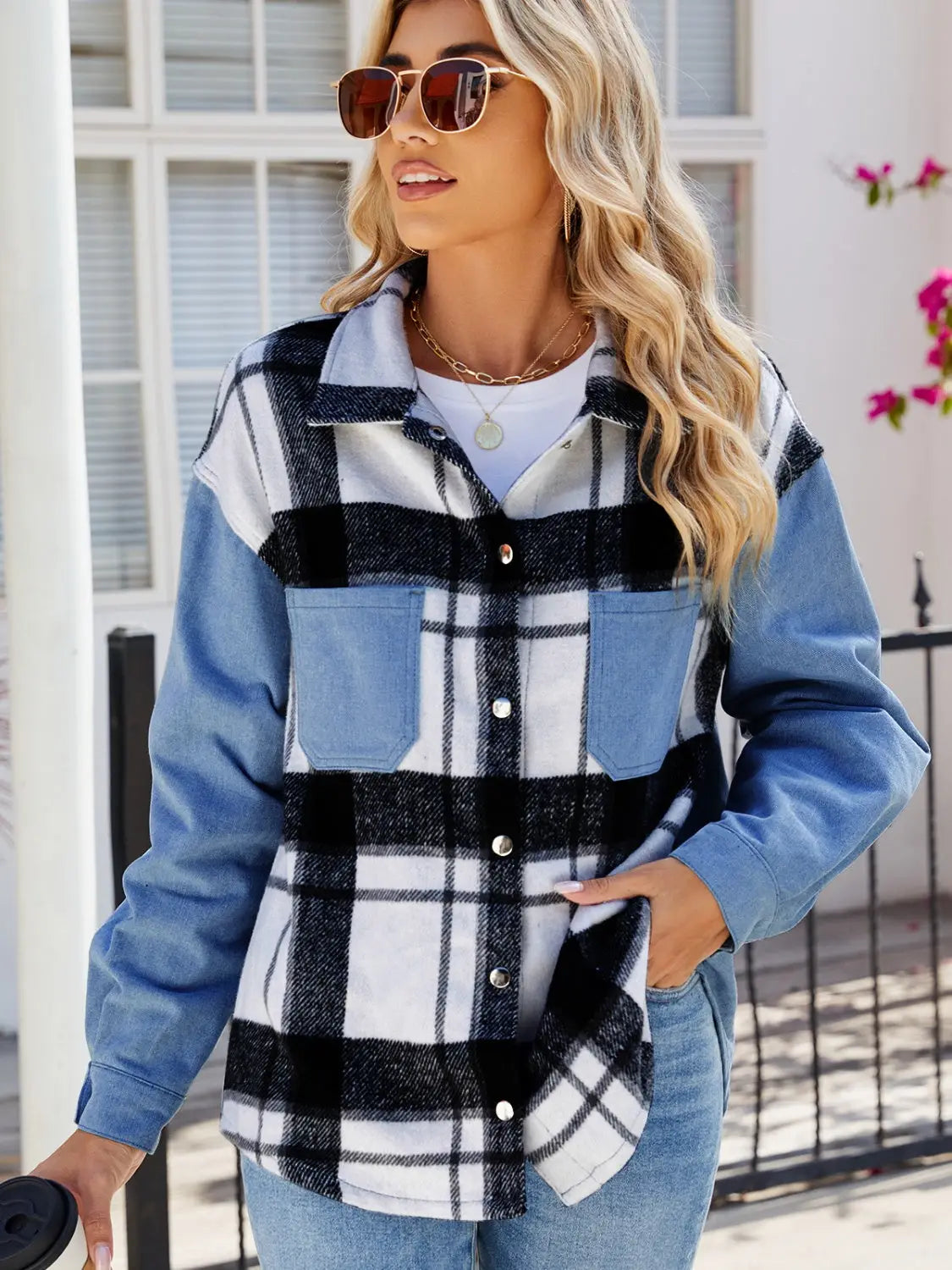 Woman wearing pocketed plaid snap down denim jacket with black and white pattern and blue denim sleeves outdoors