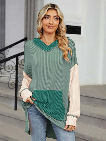 Woman wearing a long sleeve double take contrast hooded top with pocket in green and beige on steps outdoors