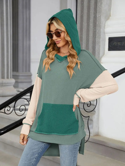 Woman wearing a green and beige double take contrast hooded long sleeve top with pocket and sunglasses outdoors