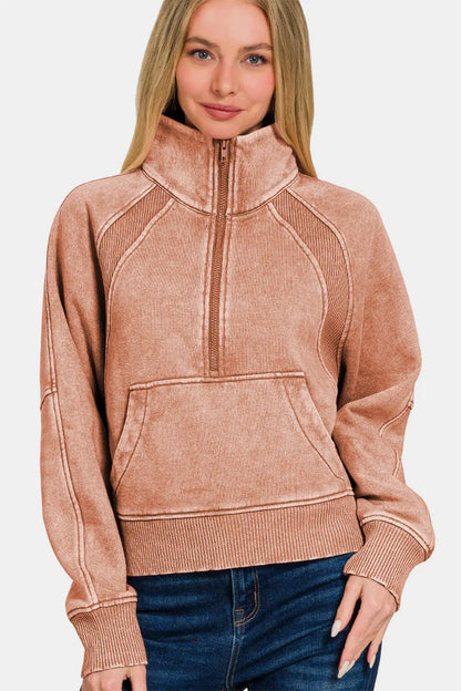 Woman wearing a Zenana acid washed half zip fleece sweatshirt with kangaroo pocket and ribbed cuffs in a dusty rose color