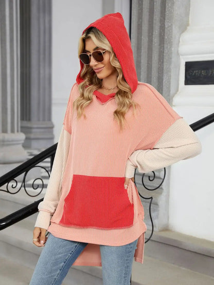 Woman wearing a color block ribbed hooded long sleeve top with front pocket and sunglasses outdoors