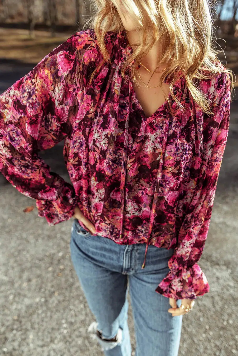 Woman wearing a floral printed tie neck blouse with flounce sleeves paired with blue jeans outdoors