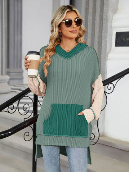 Woman wearing a color block double take contrast hooded long sleeve top with pocket holding a coffee cup outdoors